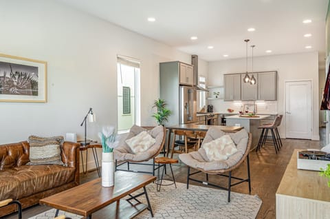 Unit 1: Welcoming living area with a vibrant green accent wall, large Smart TV, and plush seating arranged to take in the serene outside views.