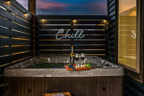 Unwind in a romantic hot tub with wine under evening lights!