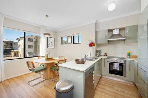 Prepare meals effortlessly in a well-lit kitchen featuring light-colored cabinetry, a window with a view, and modern stainless steel appliances, creating a functional and inviting culinary area.
