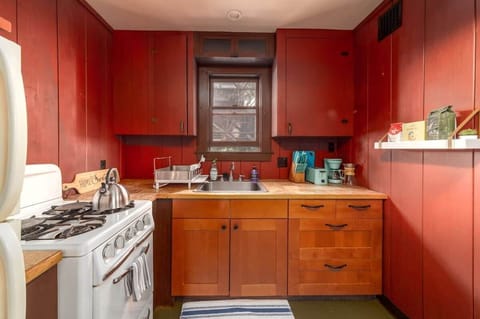 Kitchen with a small footprint but abundant features: gas stove, full fridge, toaster, two coffee maker and a small coffee bar.