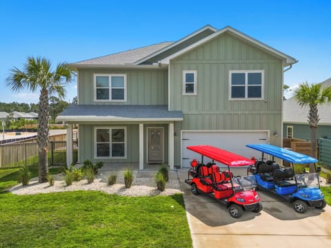 Modern beach house with golf carts ready for coastal adventures in a palm-lined neighborhood.