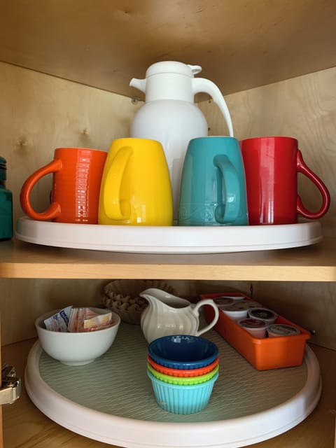 Mugs and other coffee supplies in corner cabinet above 