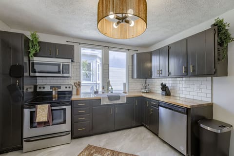 Modern kitchen with stainless appliances, wood countertops, and subway tile.