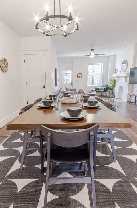 Enjoy meals at the spacious dining table with seating for six. The table is beautifully set with full dinnerware and cutlery, offering a warm and welcoming space to dine together.