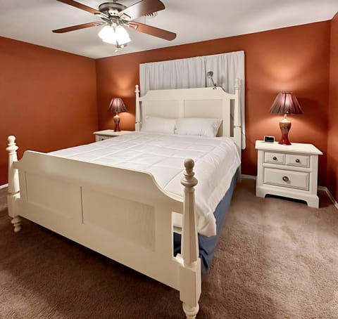 Spacious and cozy bedroom featuring a plush king-size bed with crisp white linens, warm accent lighting, and matching nightstands.