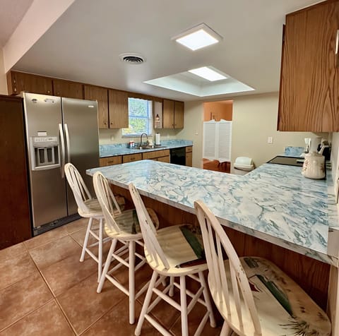 Whip up meals in this bright, fully equipped kitchen featuring a large marble-style counter, bar seating for four, stainless steel fridge, and plenty of cabinet space.