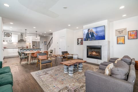 Unit 4: Welcoming living area with a vibrant green accent wall, large smart TV, fireplace, and plush seating arranged to take in the serene outside views. (1st Floor)