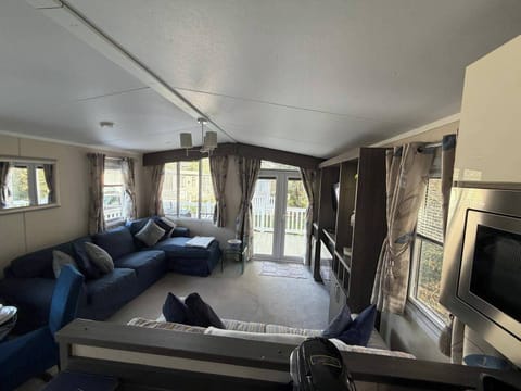 Open plan living area with a 3 seat corner sofa and a 2 seater sofa, patio doors opening onto the front balcony.