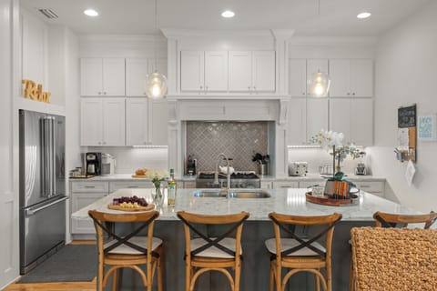 Bright, chef-style kitchen with expansive island seating, custom cabinetry, and premium appliances—perfect for gathering and entertaining.