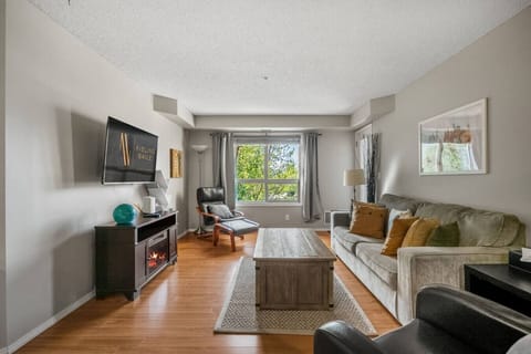 Living room with a Smart TV, cozy seating options, electric fireplace and walkout access to the balcony.