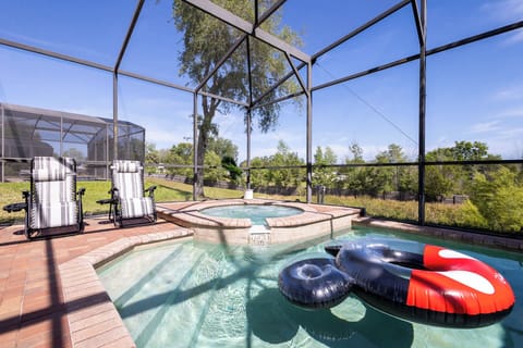 Back screened in patio with outdoor seating, grill, pool, and hot tub