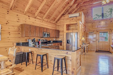 Generous kitchen space featuring sleek granite counters and a breakfast bar for 3. A supplemental A/C unit is positioned above the refrigerator.