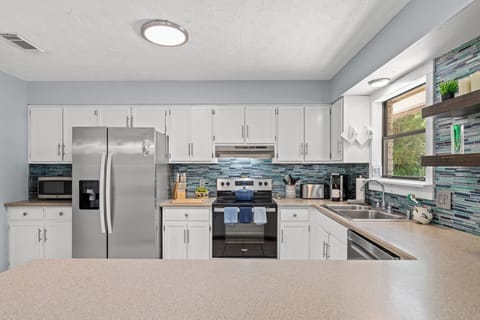 Bright and modern kitchen featuring stainless steel appliances, a full suite of cookware, and plenty of counter space for preparing meals. Thoughtful touches and open shelving add style and convenience—perfect for everything from quick breakfasts to family dinners.