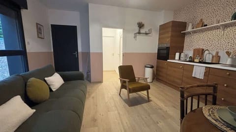 Espace salon avec canapé convertible, télévision et coin repas pour quatre personnes, ouvert sur la cuisine.