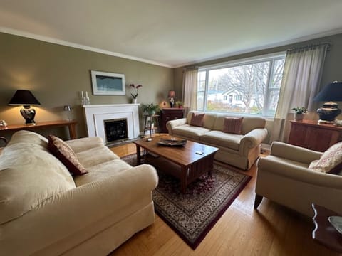 Cozy charm meets timeless style—soft seating, a glowing fireplace, and big windows make this space shine.