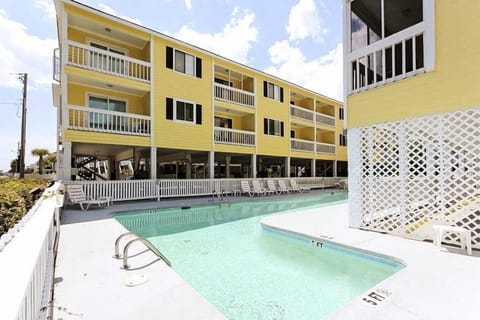 Enjoy sunny days by the outdoor pool at Sandy Shores III, just steps away from the beach, in this vibrant 1-bedroom condo featuring a private balcony.