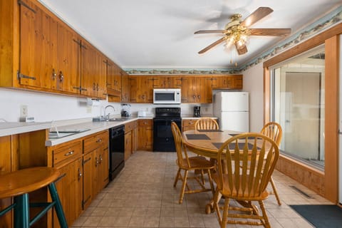 Rustic full kitchen with wood cabinetry, modern appliances, and a dining area for family meals.