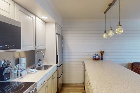 Fully equipped kitchen with stainless steel appliances, coffee maker, blender, and everything needed to prepare meals or beach snacks.