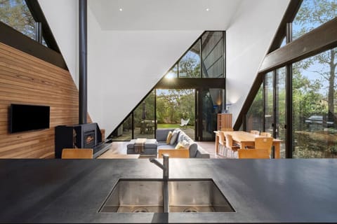 Expansive glass walls frame the open-plan living and kitchen space, filled with natural light and warmth.