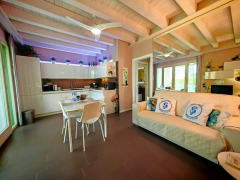 Bright living room with fully equipped kitchen and modern dining area. The space, featuring exposed beams and large windows, offers a cozy and refined atmosphere, ideal for relaxing or sharing meals with the family.