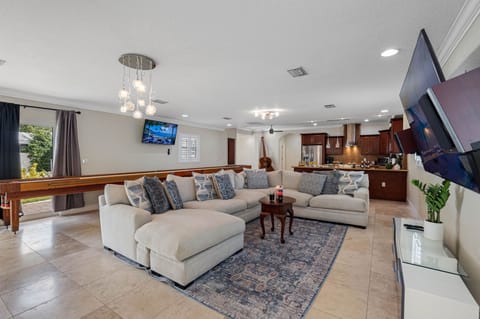 Designed for socializing, this open-concept living room offers a spacious sectional, a shuffleboard table for friendly competition, and dual flat-screen TVs for immersive entertainment.