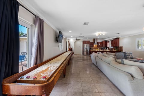 This game space features a vintage shuffleboard table and mounted TV, ideal for casual entertainment.