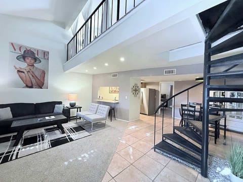 The living room is bright and open with soaring vaulted ceilings. A striking spiral staircase leads up to the loft, adding a unique touch and making the space feel even more airy and stylish. Perfect for relaxing or entertaining.