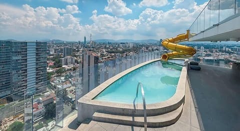 Shared rooftop pool w/ sweeping city views & a winding waterslide for a refreshing dip above the skyline