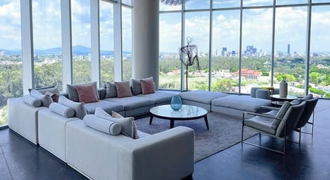 Shared living room w/ plush seating & floor-to-ceiling windows framing sweeping city views