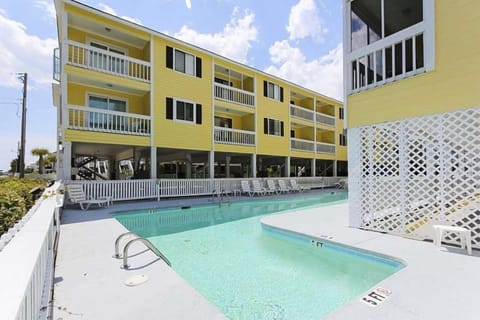 Relax by the seasonal outdoor pool at Sandy Shores III, a bright and inviting 2-bedroom condo conveniently located just steps from the beach.