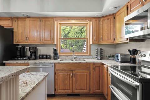 Fully stocked kitchen with 4 barstools at the breakfast bar, complimentary coffee and tea station, and visibility to the living room and back yard.