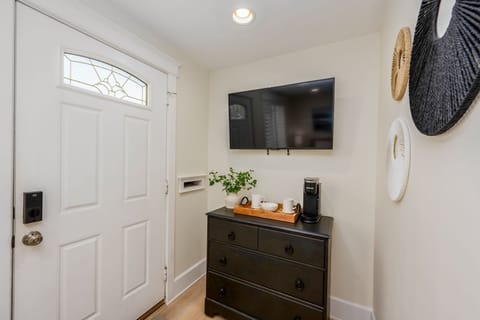 Step into a welcoming entryway designed for both comfort and convenience! This stylish space features a sleek black console with ample storage, a mounted Smart TV for entertainment, and a coffee & tea station. Perfect for staring your day.