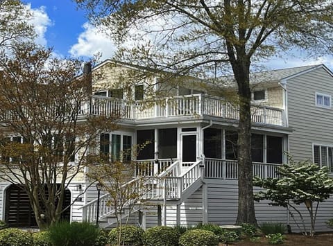 This charming vacation rental in Bethany Beach boasts a welcoming exterior with a spacious screened porch, multiple decks, and an elevator, inviting guests to enjoy the tranquil surroundings.
