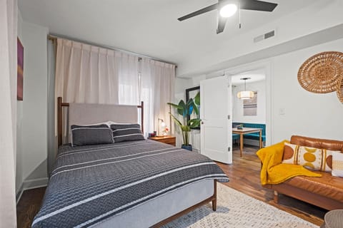 Cozy queen bedroom with plush bedding, ceiling fan, and soft natural light—perfect for unwinding after exploring the Plaza.
