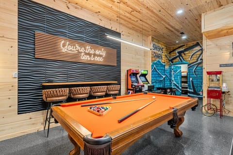 Welcome to Smoky’s Charm — where modern design meets classic fun!  From the vibrant pool table and arcade corner to the cheeky neon sign and custom mural, this family-friendly game room is the heart of the cabin. Let the good times roll!