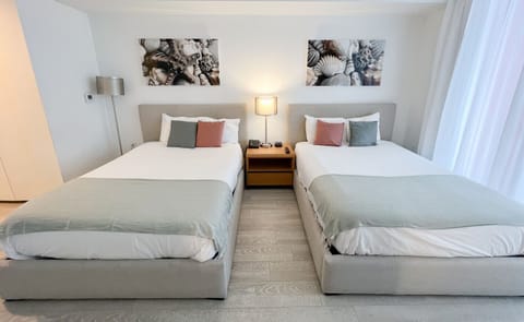 Spacious bedroom with a two beds, flat-screen TV, and bright natural lighting.