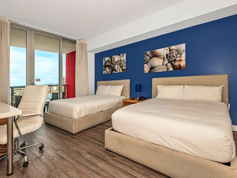 Spacious bedroom with a king-size bed, flat-screen TV, and bright natural lighting.