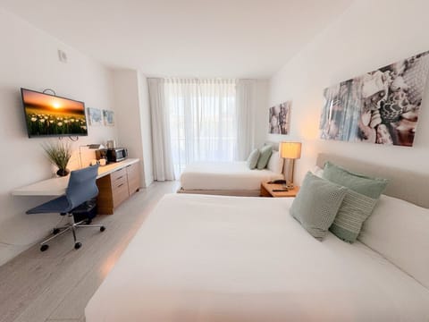 Spacious bedroom with a two beds, flat-screen TV, and bright natural lighting.