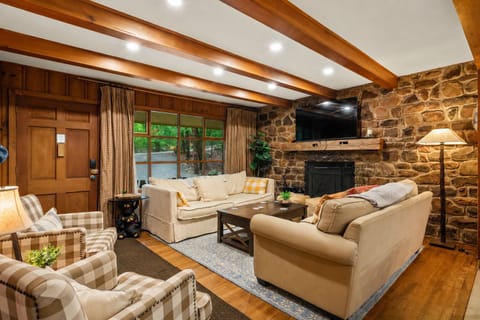 Cozy up in this warm and inviting living space with rustic wood beams, plush seating, and the perfect setup for movie nights after a day outdoors.