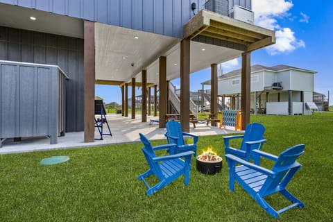 Cozy fire pit with bright blue chairs on a lush green yard — perfect for evening chats and s`mores