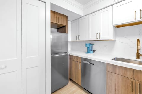Modern kitchen with stainless steel appliances, full-size fridge, dishwasher, and sleek finishes—ideal for extended stays or home-cooked meals.