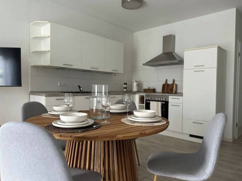 Moderne, helle Küche mit kompletter Ausstattung und rundem Esstisch – ideal zum gemeinsamen Kochen und Essen in der Ferienwohnung.
