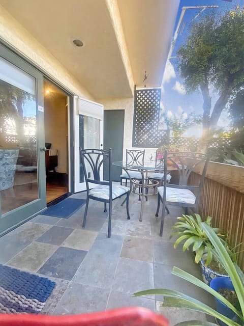  Tiled patio with seating for four, surrounded by plants and natural light.