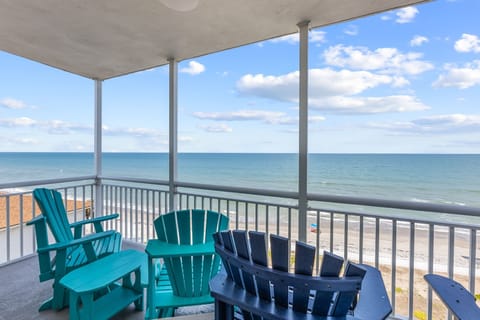 Relax on the covered balcony with colorful chairs overlooking the ocean and beach.