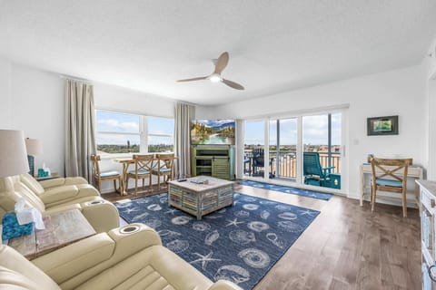 Bright living room with coastal decor and balcony access overlooking the neighborhood.