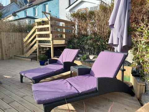 Decked area with stairs from back door and sun loungers.