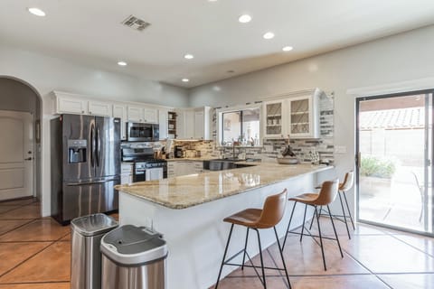 Full kitchen with granite island and barstools.