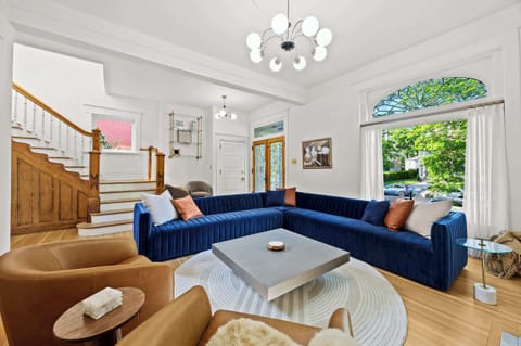 Living Room: Indulge in the vibrant elegance of our spacious living room, featuring a plush, oversized blue velvet sectional perfect for relaxing after exploring the city's charm.