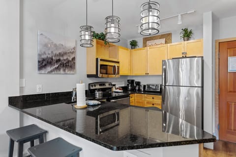 The full kitchen features stainless steel appliances, and breakfast bar seating 3.