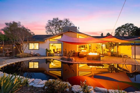 Resort-style backyard with a serene pond, firepit lounge, and sunset canopy vibes.